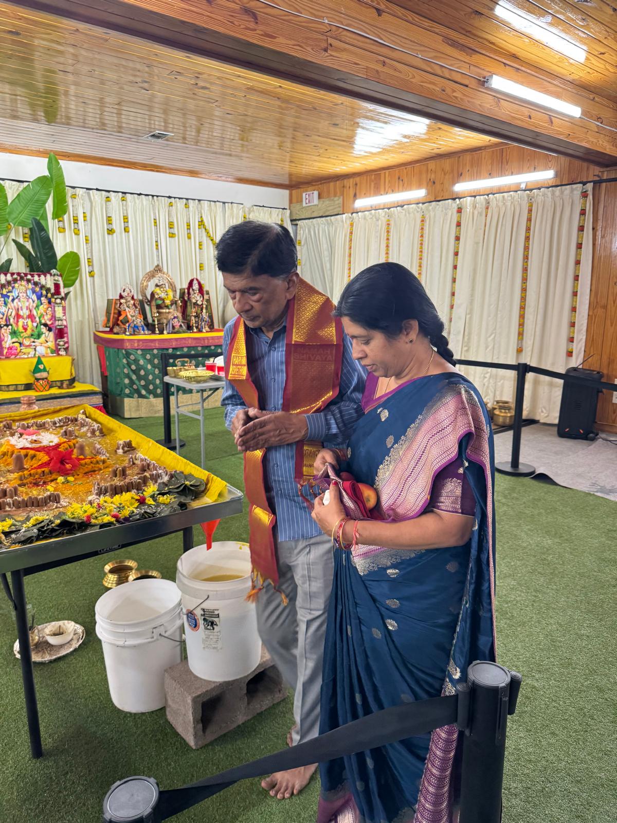 Close-up of a decorated Shiva Linga being bathed with water and flowers during a Hindu ritual.